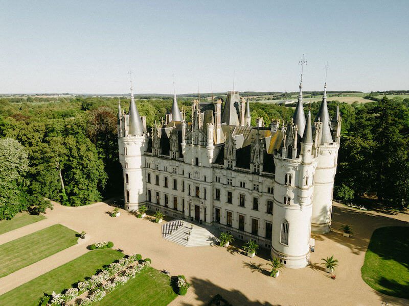 Vue d’un château mariage somptueusement éclairé, entouré de jardins à la française, idéal pour célébrer un mariage de conte de fées.